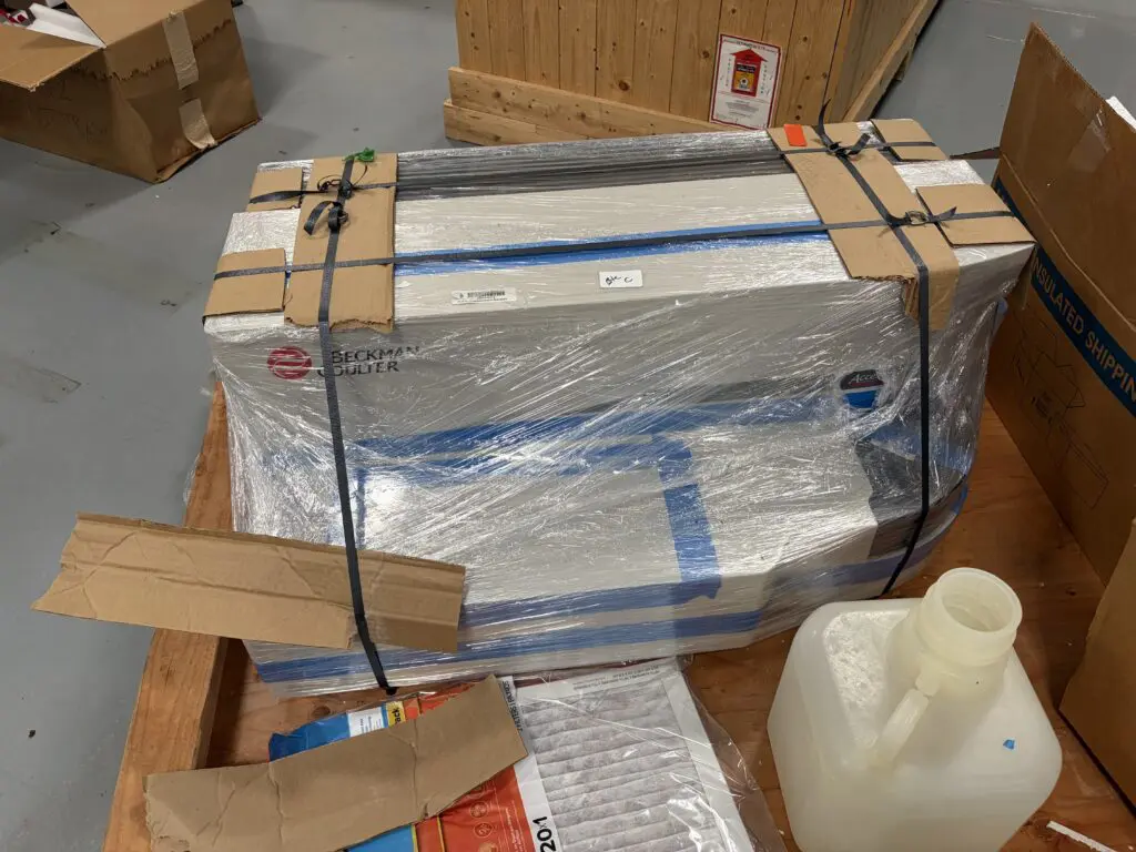 Lab instrument wrapped and strapped to a wooden pallet for freight shipping